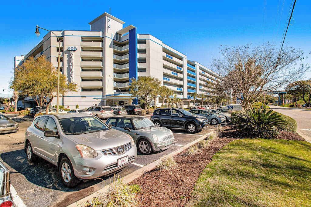A multi-story parking garage with a modern design, adjacent to a hotel with a visible sign.