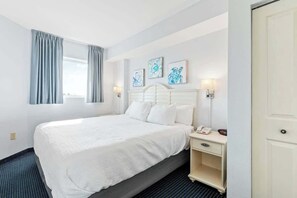 A hotel room with a bed, bedside table, lamp, and artwork on the wall. - Harbourgate Unit 0404 (North Myrtle Beach)