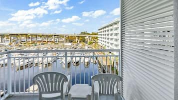 A balcony with white chairs and a view of a marina with boats.