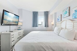 A hotel room with a bed, a TV, a dresser, and artwork on the walls. - Harbourgate Unit 0404 (North Myrtle Beach)