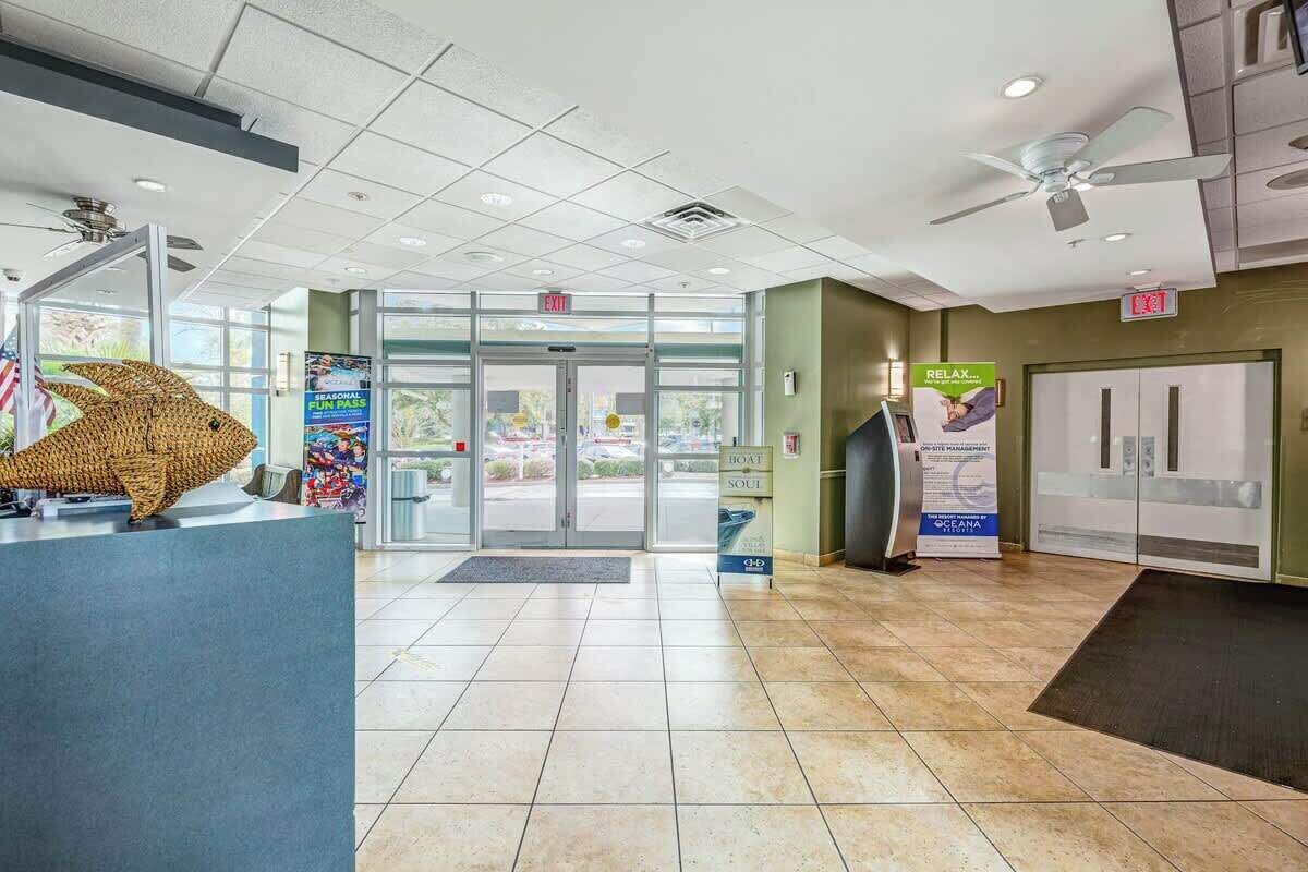 A reception area with a glass door entrance, a reception desk, and a ceiling fan.