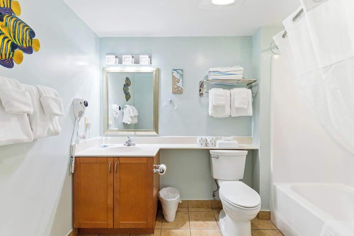 A bathroom with a wooden cabinet, a toilet, a sink, and a bathtub.