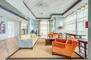 Uma sala de estar ampla com sofá, poltronas, mesa de centro e mesa de jantar.