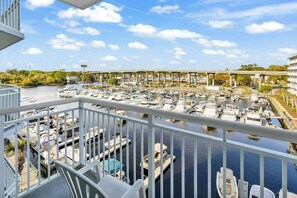 A marina with boats docked, a bridge in the background, and a balcony with a railing. - Harbourgate Unit 0404 (North Myrtle Beach)