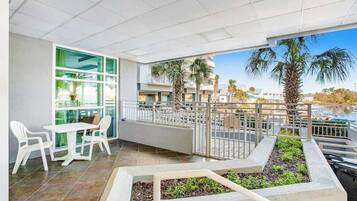 Un balcon doté d’un espace repas, de palmiers et offrant une vue sur une étendue d’eau.