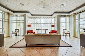 A spacious lobby with a central sofa, two side tables, and large windows providing natural light. - Harbourgate Unit 0404 (North Myrtle Beach)