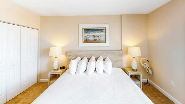 A hotel room with a large bed, two bedside tables with lamps, a framed picture on the wall, and a white wardrobe. - Harbourgate Unit 0320 (North Myrtle Beach)