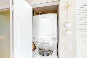 A compact laundry room with a front-loading washing machine and a built-in dryer. - Harbourgate Unit 0320 (North Myrtle Beach)