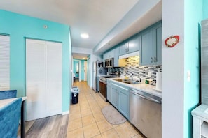 A kitchen with teal cabinets, a microwave, and a tiled backsplash. - Harbourgate Unit 0410 (North Myrtle Beach)
