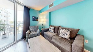 Een woonkamer met een bank, fauteuil en salontafel. Er is een raam met uitzicht op gebouwen.