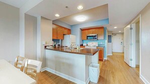 A modern kitchen with wooden cabinets, a central island, and a dining area with chairs. - Harbourgate Unit 0522 (North Myrtle Beach)