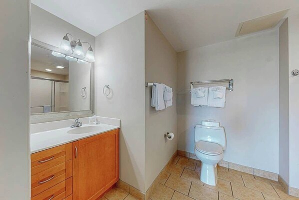 A bathroom with a white sink, wooden vanity, a mirror with lights, a toilet, and a towel rack. - Harbourgate Unit 0522 (North Myrtle Beach)