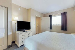 A hotel room with a bed, a television on a dresser, a window with curtains, and a door. - Harbourgate Unit 0522 (North Myrtle Beach)