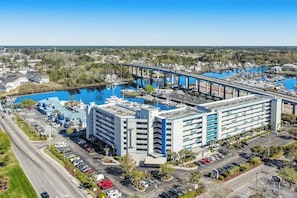 Ein mehrstöckiges Hotel mit Parkplatz und einem Hafen mit Booten.