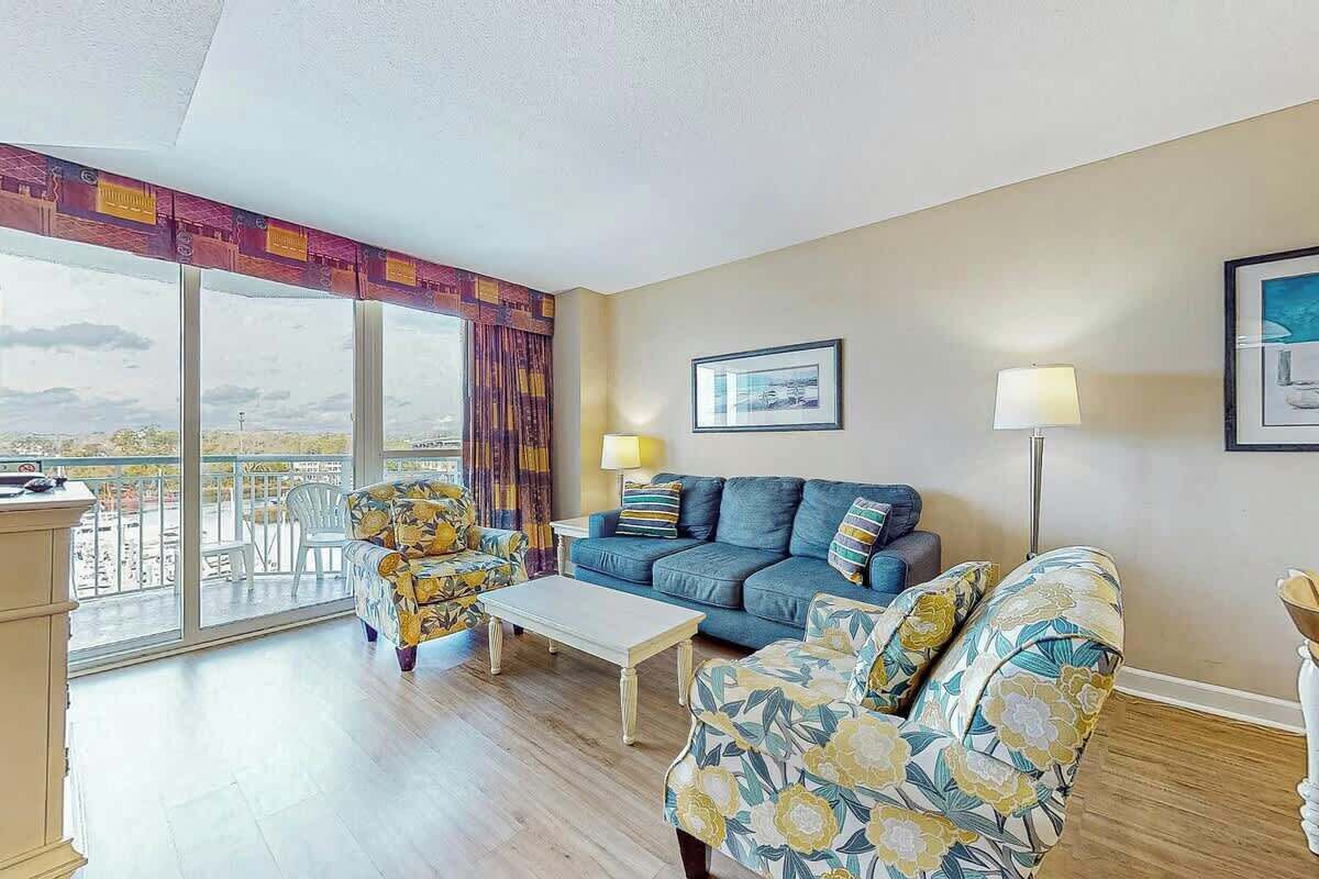 Un salon comprenant un canapé, des fauteuils, une table basse et un balcon avec vue.