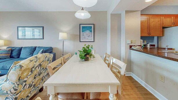 A dining area with a table, chairs, and a plant centerpiece. There is a sofa and a lamp in the background. - Harbourgate Unit 0522 (North Myrtle Beach)