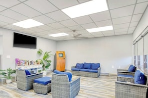 A room with wicker furniture, a flat-screen TV, and a wooden cabinet. - Ocean Park Resort 0322 (Myrtle Beach)