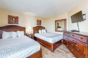 A hotel room with two beds, a dresser, a TV, and artwork on the walls. - Ocean Park Resort 0322 (Myrtle Beach)
