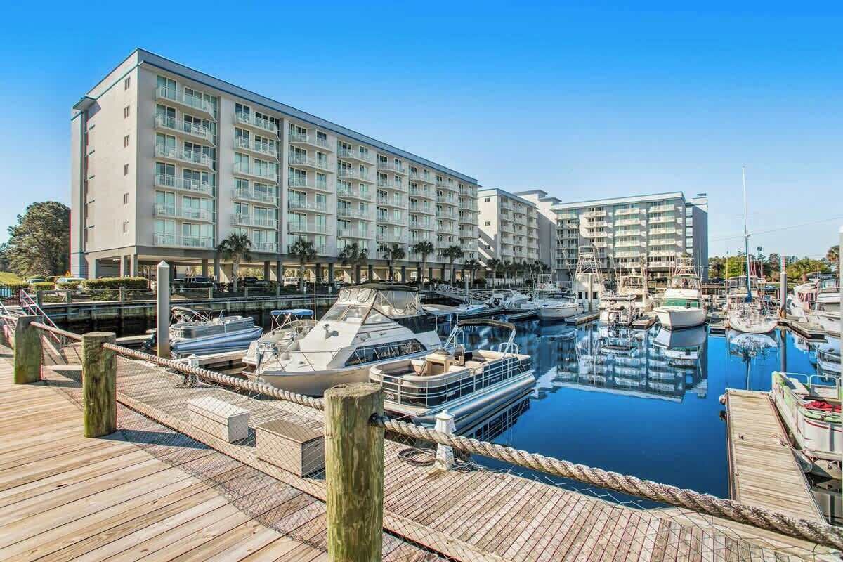 Ein Yachthafen mit vertäuten Booten, eine Holzsteganlage und ein mehrstöckiges Hotelgebäude mit Balkonen.