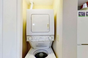A compact washer and dryer unit in a small laundry room with a single door and a visible vent pipe above the dryer. - Harbourgate Unit 0610 (North Myrtle Beach)