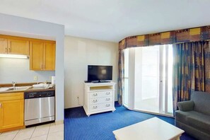 A compact hotel room with a kitchenette, a flat-screen TV, a sofa, and a large window with curtains. - Harbourgate Unit 0610 (North Myrtle Beach)