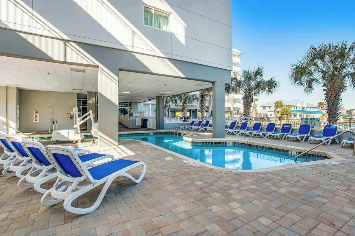 A pool area with lounge chairs and a lifeguard sign.