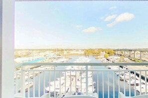 A marina with boats docked, a clear sky, and a bridge in the distance. - Harbourgate Unit 0626 (North Myrtle Beach)