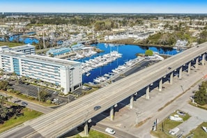 A marina with multiple boats docked, a large building with a blue roof, and an overpass above the road. - Harbourgate Unit 0626 (North Myrtle Beach)