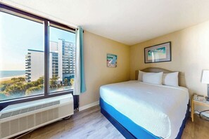 Ein Hotelzimmer mit einem großen Bett, Blick auf die Stadt und einem Fenster mit Vorhängen.