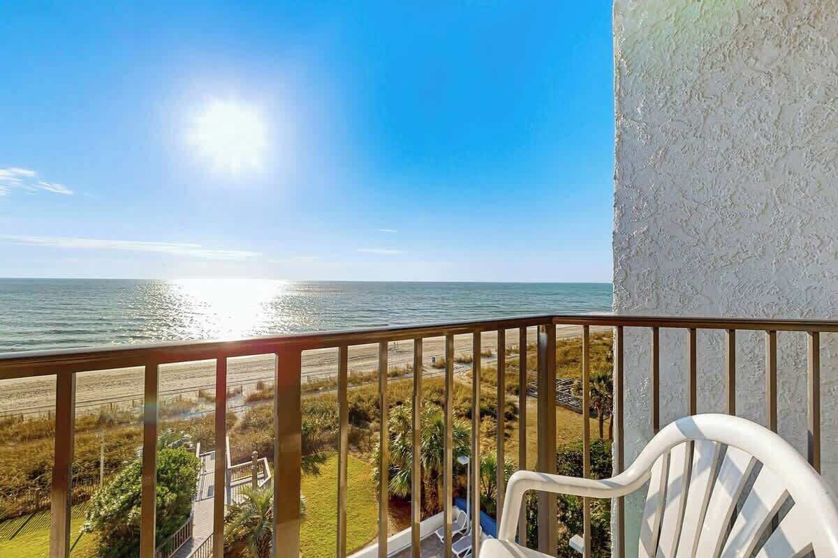 A balcony with a view of the ocean and beach.