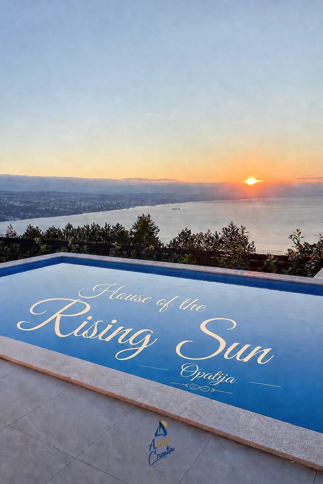 A swimming pool with a view of a cityscape and the sun setting in the background.