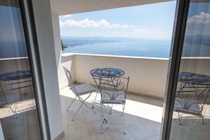 A balcony with a view of the sea and a cityscape, featuring a table and two chairs. - 4-BR Sea-View Villa with Pool near Opatija (Veprinac)