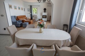 Un coin repas avec une table ronde, six chaises et un vase de fleurs.