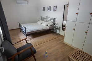 Une chambre à coucher avec un lit, une chaise, une armoire et une petite table.