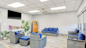 A room with wicker furniture, a flat-screen TV, a ceiling fan, and a wooden cabinet. - Ocean Park Resort 0722 (Myrtle Beach)