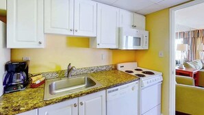 A compact kitchen with white cabinets, a microwave, a stove, and a sink. - Ocean Park Resort 0722 (Myrtle Beach)