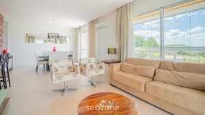 A spacious living area with a sofa, armchairs, and a dining table.