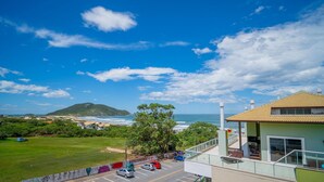 A coastal view with a building featuring a balcony overlooking the beach and ocean.