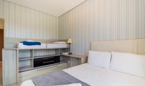 A hotel room with a bunk bed, a bedside table with a lamp, a TV, and a large bed with pillows. - Apartment Sea View in Beachfront Condo Asr0201 (Florianópolis)