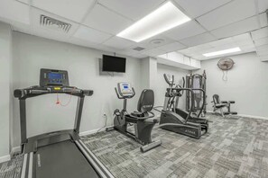 A fitness room with cardio equipment, including a treadmill and elliptical, and a wall-mounted TV. - Ocean Park Resort 0922 (Myrtle Beach)