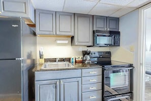 A compact kitchen with a refrigerator, microwave, stove, and oven. - Ocean Park Resort 0922 (Myrtle Beach)