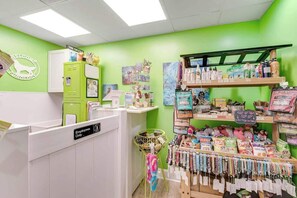 A pet grooming salon with a green wall, a reception desk, and shelves stocked with pet products. - Ocean Park Resort 0922 (Myrtle Beach)