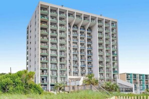 A multi-story hotel with balconies, a central staircase, and a pool area. - Ocean Park Resort 0922 (Myrtle Beach)