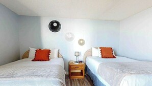 A hotel room with two beds, a nightstand with a lamp, and a wall with decorative plates. - Ocean Park Resort 0922 (Myrtle Beach)