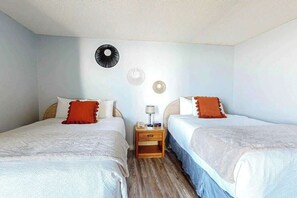 A hotel room with two beds, a nightstand with a lamp, and a wall with decorative plates. - Ocean Park Resort 0922 (Myrtle Beach)