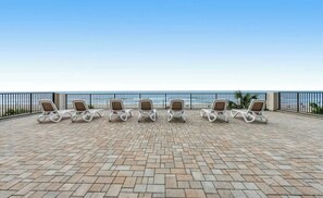 A terrace with six lounge chairs aligned in a row, overlooking a beach. - Ocean Park Resort 0922 (Myrtle Beach)