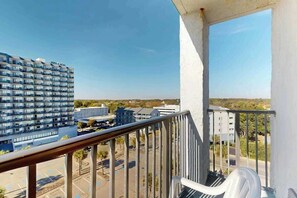En balkon med udsigt over en parkeringsplads og bygninger.