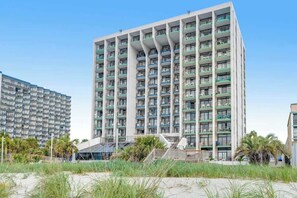 Ein Hochhaus-Hotel mit mehreren Balkonen, einer flachen Dachterrasse und einem modernen architektonischen Design.