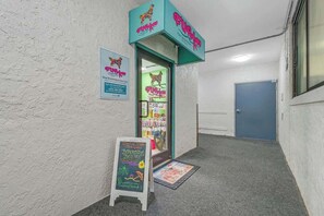 A dog grooming and day care facility with a teal sign, a chalkboard advertisement, and a door to the right. - Ocean Park Resort 1224 (Myrtle Beach)