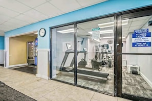 A fitness center with a treadmill, weight machines, and a sign indicating availability from 7 am to 11 pm. - Ocean Park Resort 1224 (Myrtle Beach)